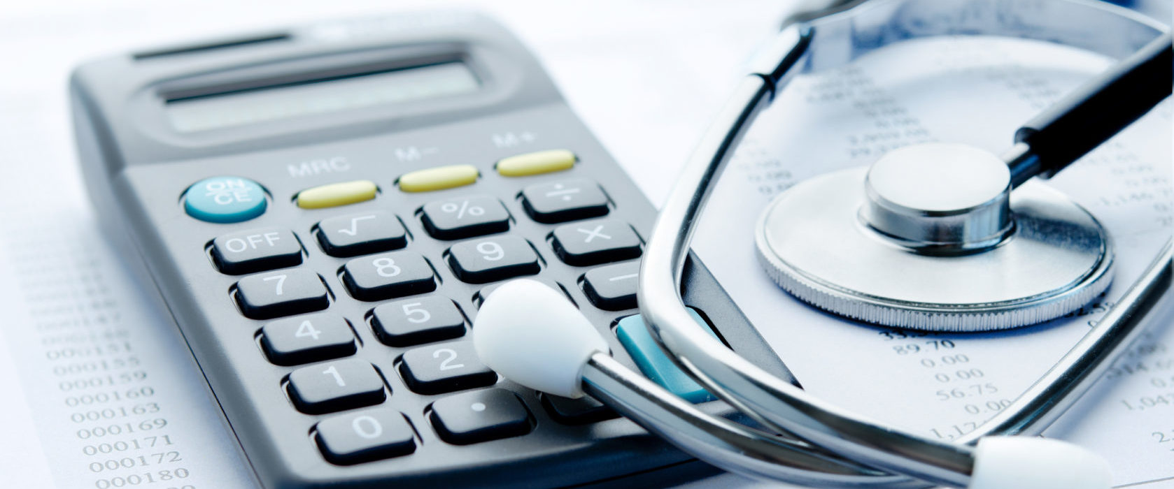 A calculator beside a stethoscope on top of paperwork